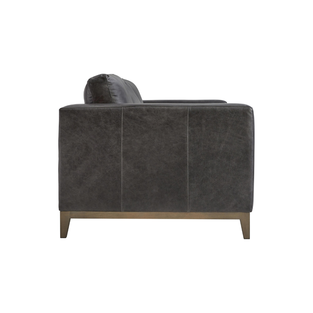 Close-up of the Bernhardt Noel 3-Seater Sofa showing dark leather upholstery with track arm detail and tapered wooden leg