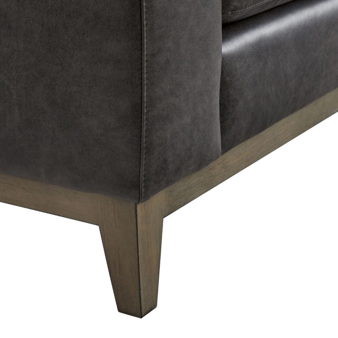 Close-up of the Bernhardt Noel 3-Seater Sofa showing dark leather upholstery with track arm detail and tapered wooden leg