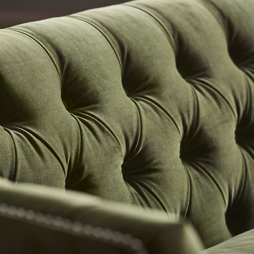 Closeup view of Duncan Tufted Sofa in green upholstery with deep button-tufting, nailhead trim, and wooden legs – elegant 2-seater design