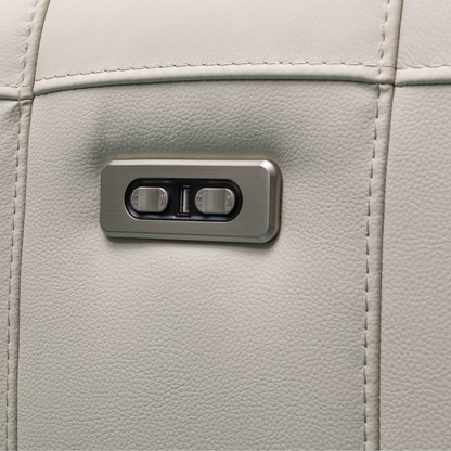 Close-up of power reclining controls on the Klaussner Capri Chair, featuring sleek metal buttons for adjustable headrest and footrest on beige leather upholstery.