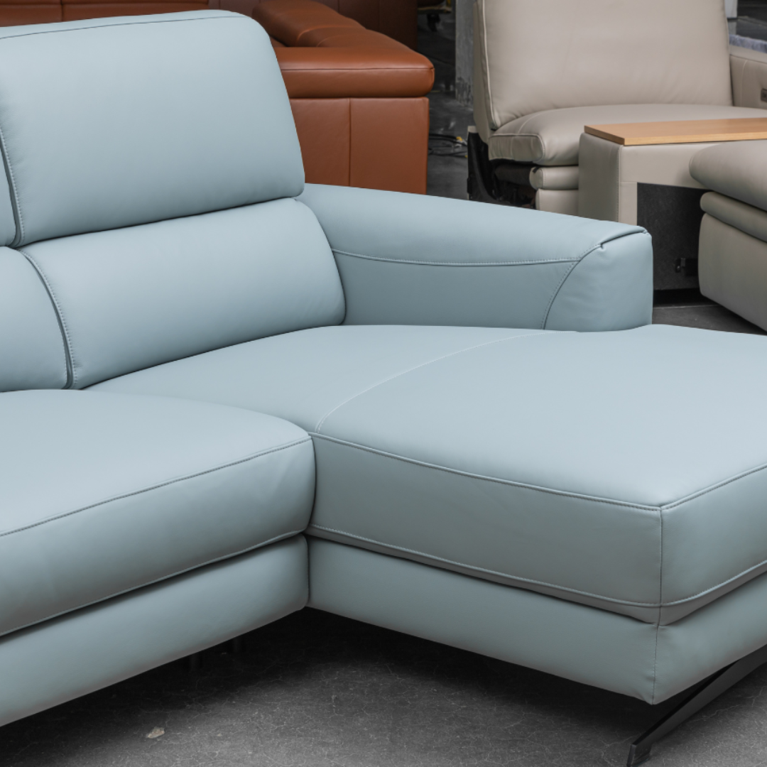 Close-up corner view of light blue leather sectional sofa showing L-shaped configuration with plush cushioned seating and clean modern lines for comfort design furniture
